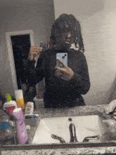 a man taking a picture of himself in a bathroom mirror with a bottle of xtreme shampoo in front of him