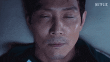 a close up of a man 's face with his eyes closed and a netflix logo in the background .