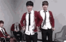two boys in school uniforms are dancing in a room .