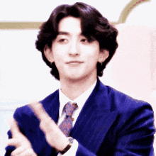a man in a suit and tie clapping his hands