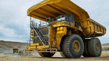 a large yellow dump truck is parked in a dirt field in a mine .