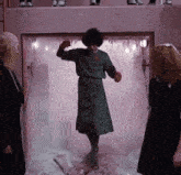 a woman in a green dress is standing in a room with a sign on the wall that says ice