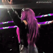 a woman with purple hair is holding a microphone in her hand .