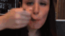 a woman is holding a spoon in her mouth and eating something .