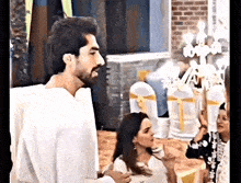 a man and a woman are standing next to each other in a room with chairs .