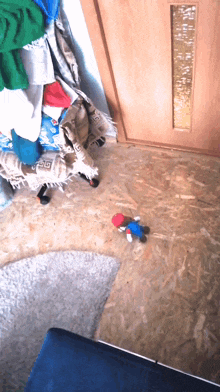 a stuffed mario doll is on the floor in front of a stack of clothes