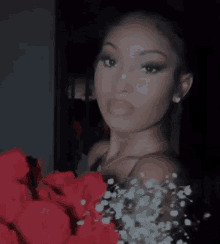 a close up of a woman holding a bouquet of red roses .