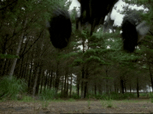 a black vehicle is flying through the air in a forest