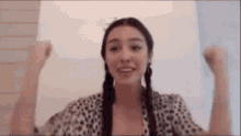 a woman wearing a leopard print shirt is raising her arms in the air .