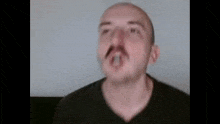 a close up of a bald man with a mustache making a funny face .