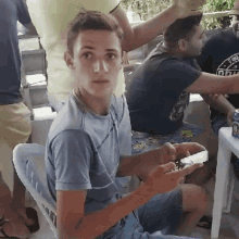 a young man in a blue shirt is sitting in a chair with a can of beer in front of him