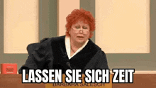 a judge with red hair and glasses is sitting in front of a microphone in a courtroom .
