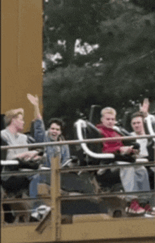 a group of people are riding a roller coaster and one of them is waving his hand