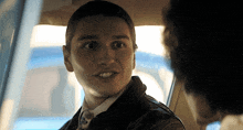 a man in a leather jacket and tie is looking at another man