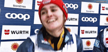a woman wearing a red hat is smiling in front of signs for wurth coop and wurth