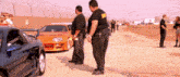 a man in a black shirt with the word security on it stands in front of a car
