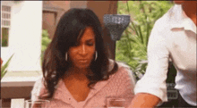 a woman in a pink shirt is sitting at a table with glasses of wine .