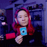 a woman with red hair wearing headphones and holding a card with an apple logo on it
