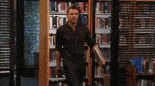 a man is walking through a library holding a folder