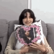 a woman is sitting on a couch holding a pillow with a picture of a person on it .