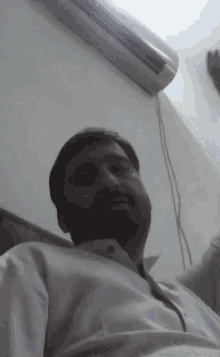 a man in a white shirt is laying on a bed in front of a wall mounted air conditioner