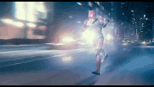 a man in a superhero costume is running down a street at night .
