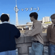 a group of young men are standing on a bridge with a tower in the background and a sign that says " l "