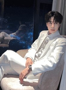a man in a white suit sits on a couch