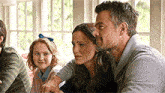 a man and a woman are sitting next to each other while a little girl looks on .