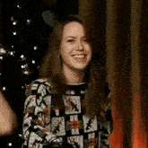 a woman is smiling in front of a christmas tree in a room .