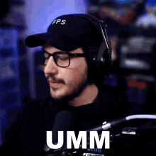 a man wearing headphones and a hat says umm in front of a microphone