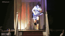 a wrestler is walking down a set of stairs with a west coast sign in the background