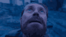 a man with a beard is looking up at the sky with his eyes closed .