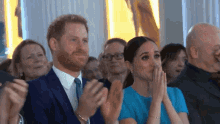 a man and a woman are sitting in a crowd clapping .