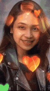 a girl in a leather jacket is smiling with hearts on her head