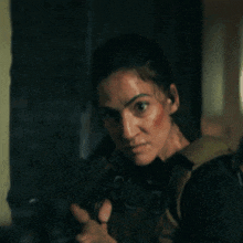 a woman is holding a gun in a dark room