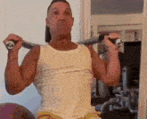 a man in a white tank top is lifting a barbell over his head