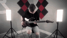 a man is playing an electric guitar in a room with acoustic panels on the wall