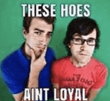 two men are standing next to each other and one of them is wearing glasses and a blue shirt .