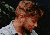 a man with a beard wearing a blue shirt looks down