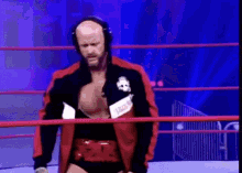 a wrestler wearing headphones and a jacket with a skull on it is standing in a ring .