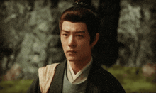 a man with a ponytail on his head looks to the side