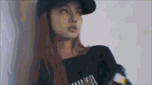 a woman wearing a baseball cap and a black shirt is standing in front of a white wall .