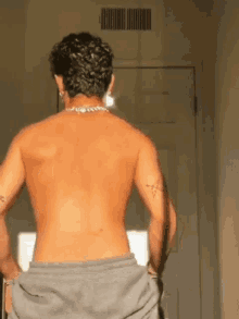 a shirtless man is standing in front of a door .
