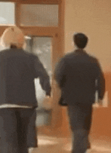 a couple of people are walking down a hallway holding hands .