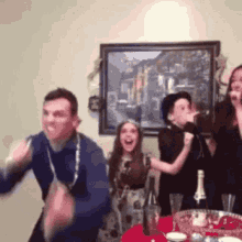 a group of people are dancing in front of a painting in a living room .