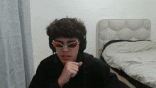 a young man wearing headphones and sunglasses has his hand on his chin