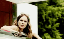 a woman is leaning out of a car window and looking at the camera .