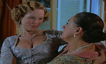 two women are standing next to each other and one has a pearl necklace
