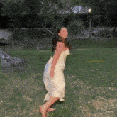 a woman in a white dress is dancing barefoot in the grass